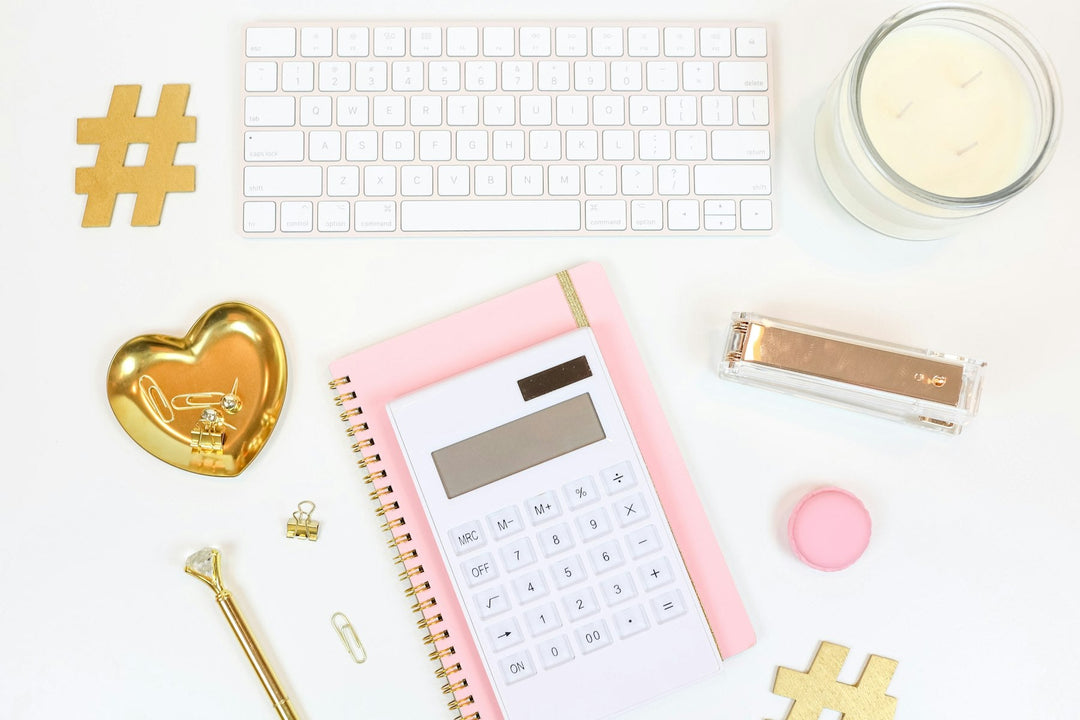 Pink calculator and gold office accessories flat lay for the hat bar profit calculator