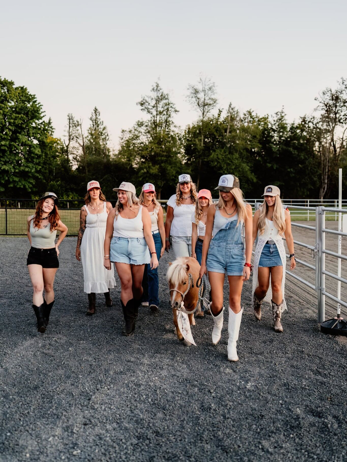 Group of cowgirls wearing custom patched trucker hats at a ranch